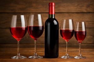 Calici di vino rosso leggero su un tavolo apparecchiato all'esterno, con piatti freschi e luce naturale