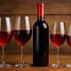 Calici di vino rosso leggero su un tavolo apparecchiato all'esterno, con piatti freschi e luce naturale
